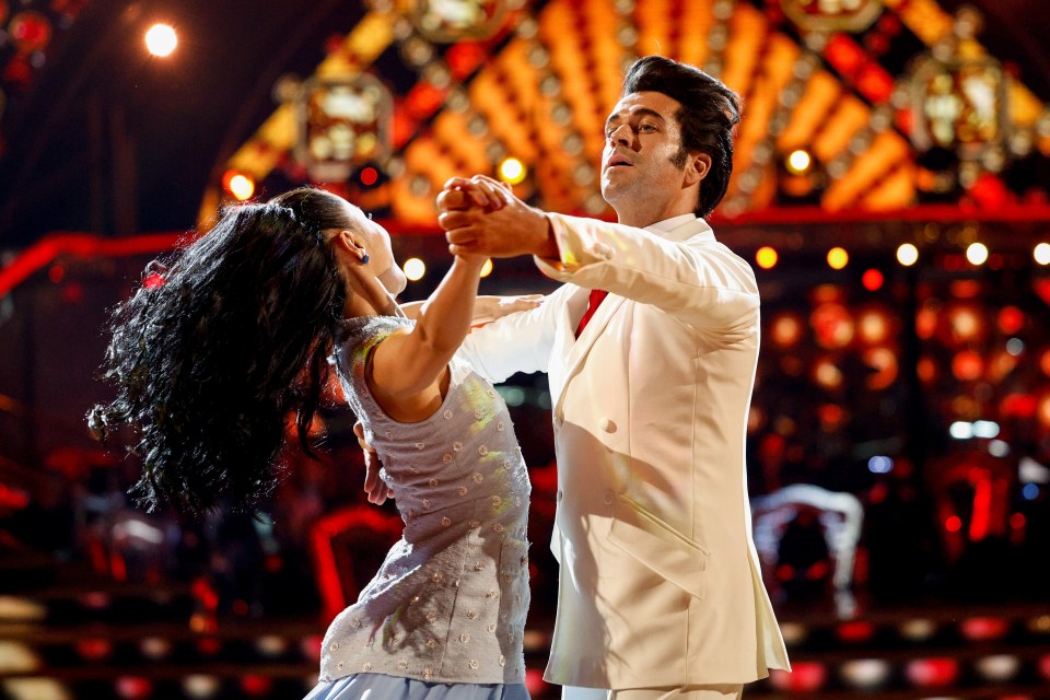 a man in a white suit is dancing with a woman in a blue dress