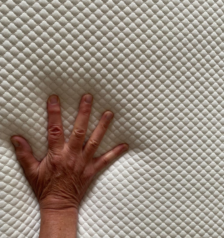 a person 's hand is laying on a white mattress