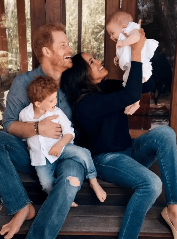 a family sits on a porch holding a baby and smiling