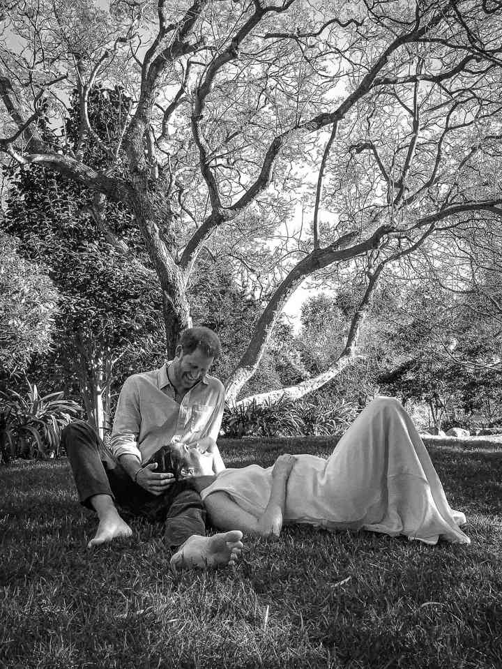 a black and white photo of a man and woman laying under a tree