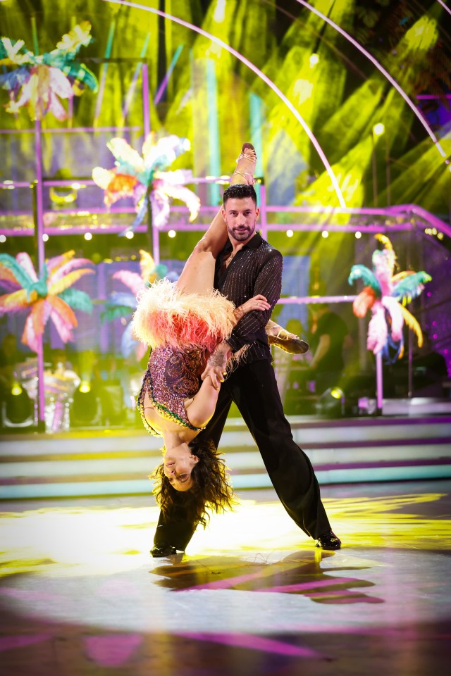 a man and a woman are dancing on a stage with flowers in the background