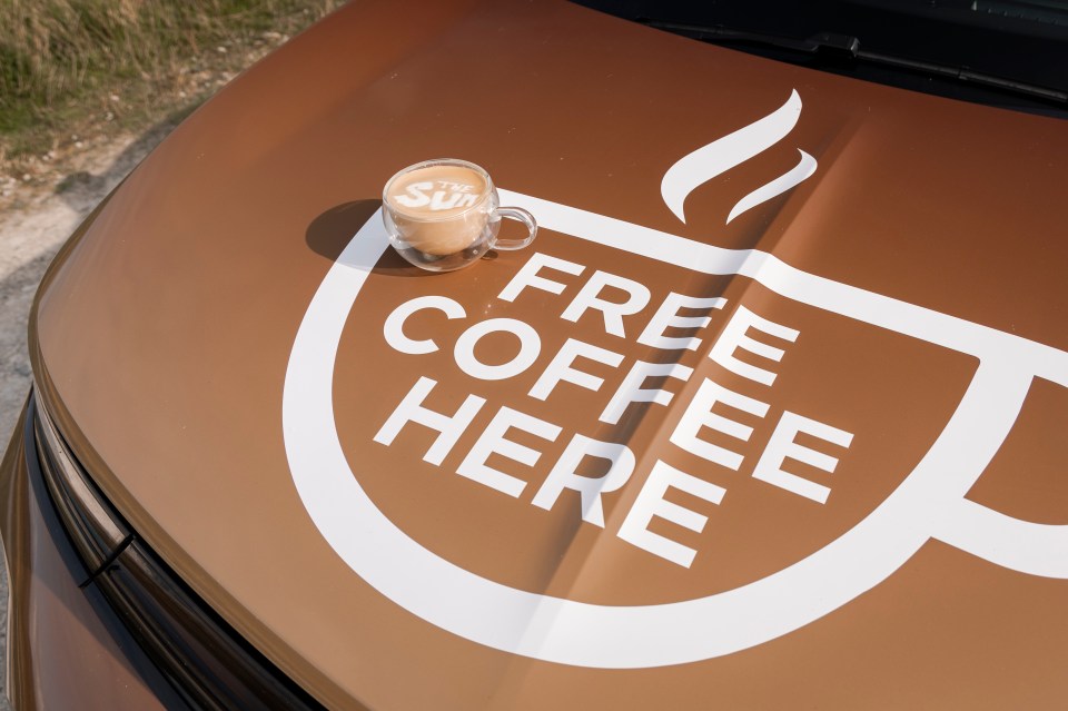 a cup of coffee sits on the hood of a car that says free coffee here