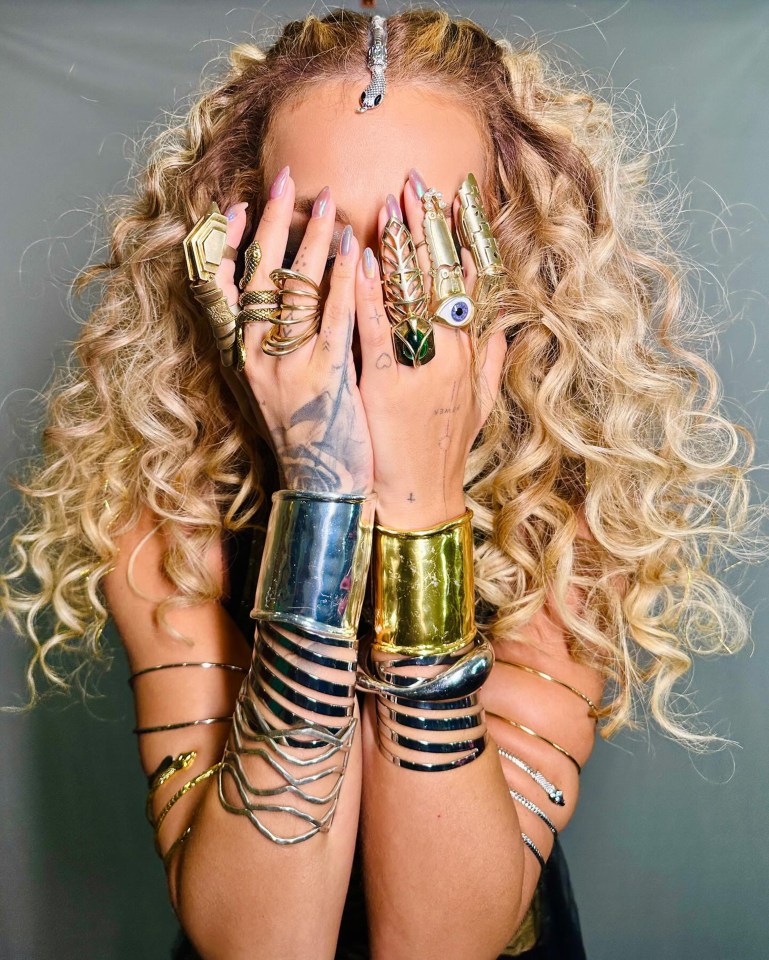 a woman covering her face with a lot of rings and bracelets