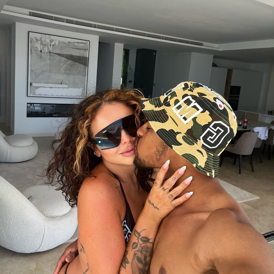 a man wearing a hat with the letter g on it kisses a woman