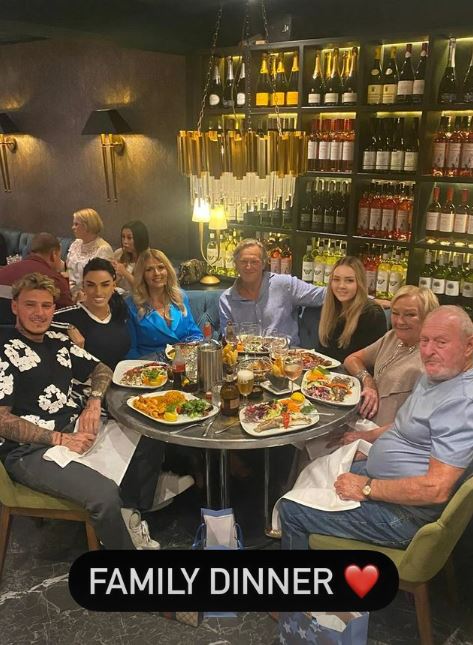 a group of people are sitting around a table with plates of food .