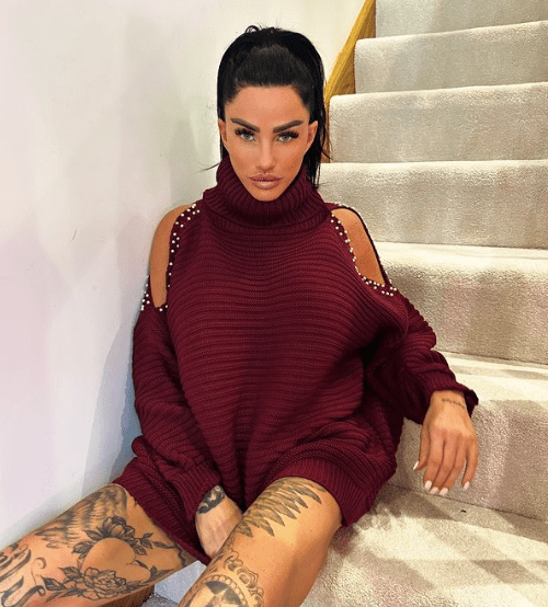 a woman wearing a maroon sweater with pearls on the shoulder sits on a set of stairs