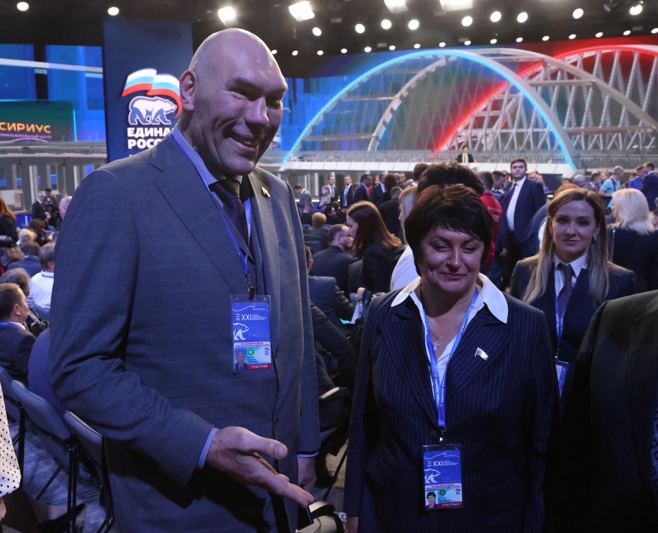a man in a suit stands in front of a sign that says единая росс