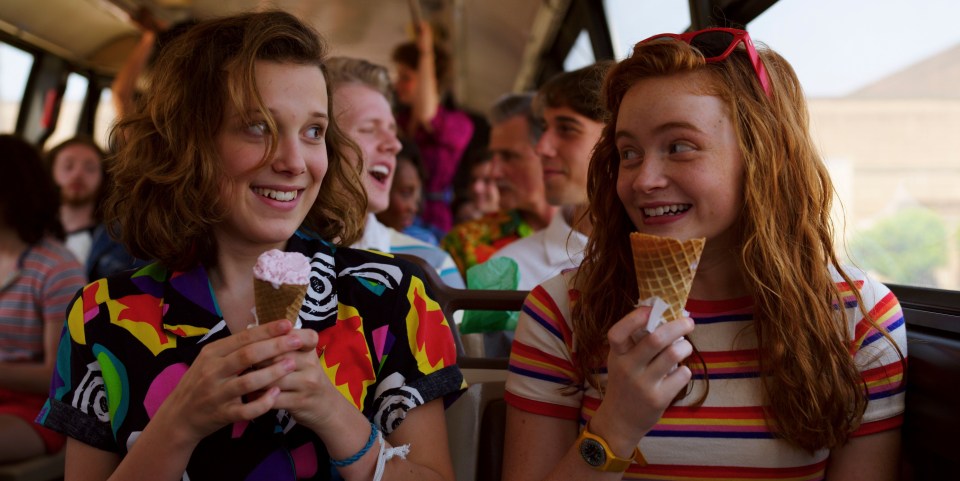 two girls are eating ice cream cones on a bus