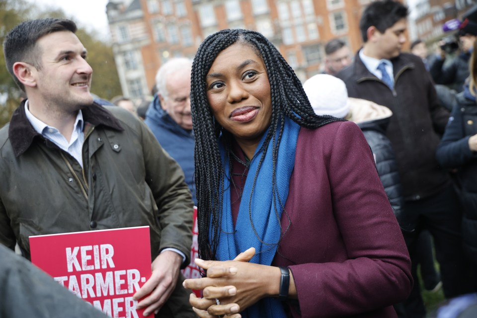 a woman holding a sign that says keir tarmer