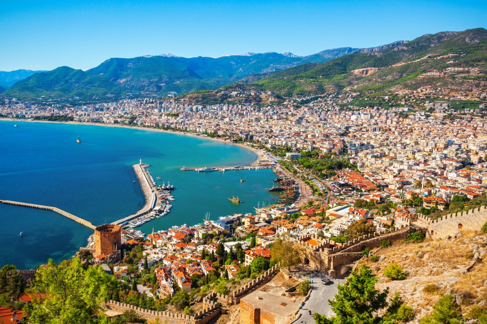 Aerial view of Alanya, Turkey, showing the Red Tower, harbor, and city skyline.
