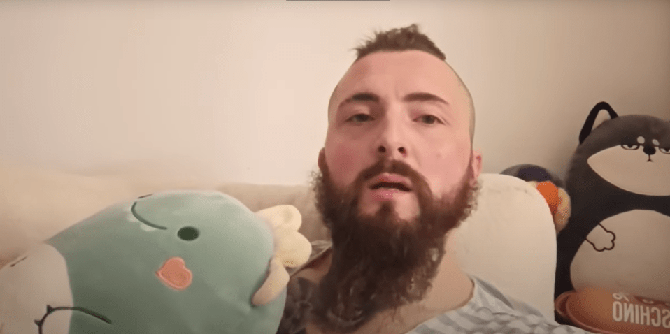 Man with a beard holding a plush toy.