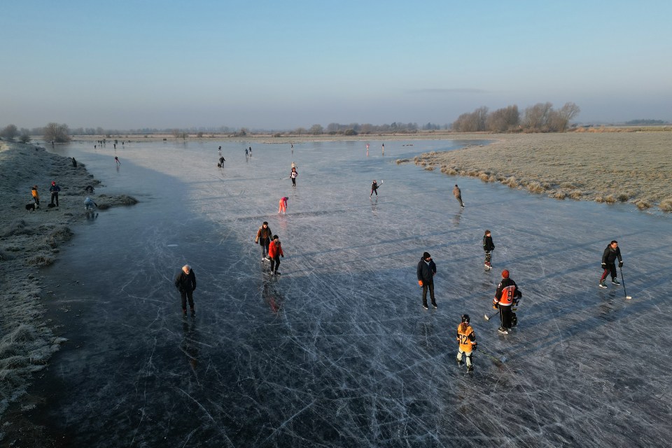 People ice skating on a frozen flooded field.