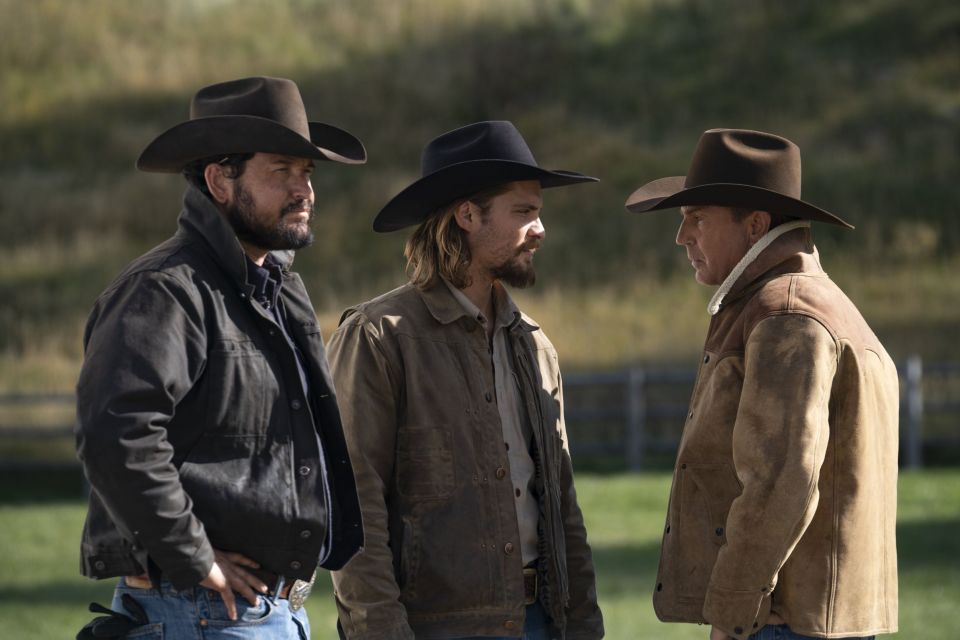 Three men in cowboy hats and jackets stand outdoors.