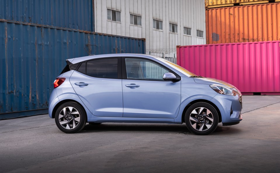 Light blue Hyundai Grand i10 parked near shipping containers.
