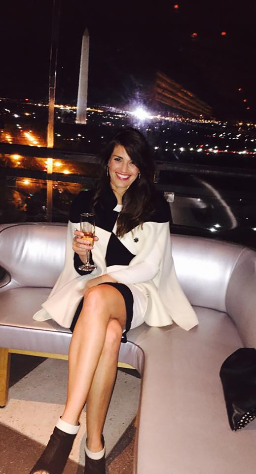 Woman sitting on a couch with a glass of champagne, Washington Monument in the background.
