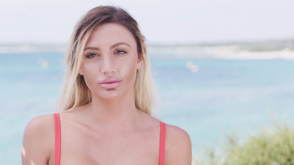 Woman in a red bikini top by the ocean.