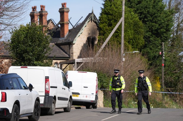 Police officers outside a fire-damaged house.