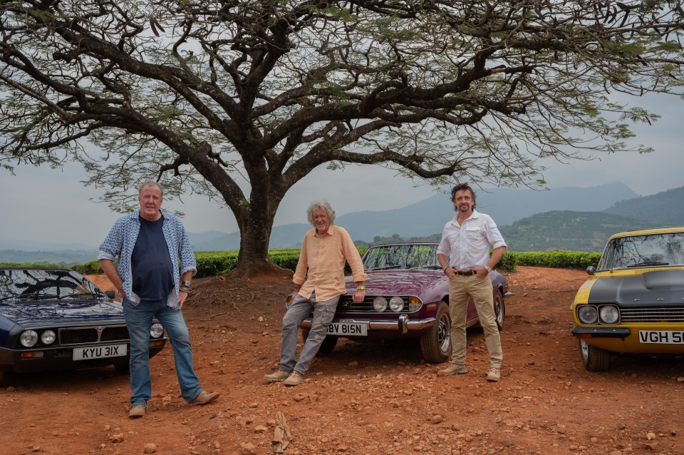 Three men standing with classic cars in Zimbabwe.