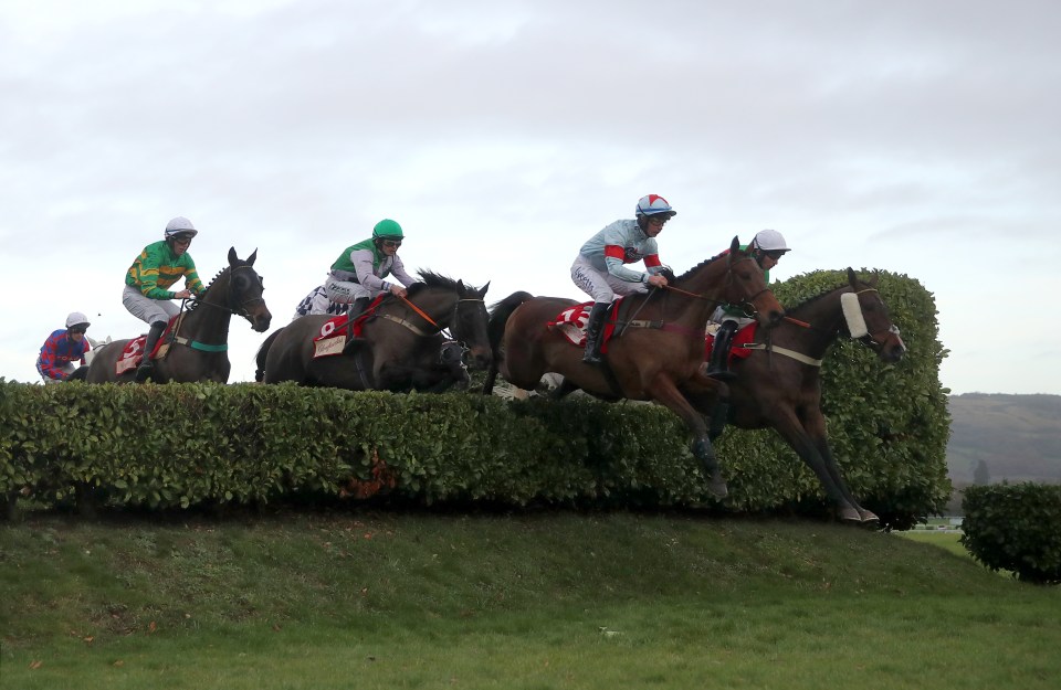 Horses and jockeys jumping a hurdle during a race.