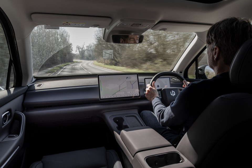 Man driving electric vehicle on a country road.