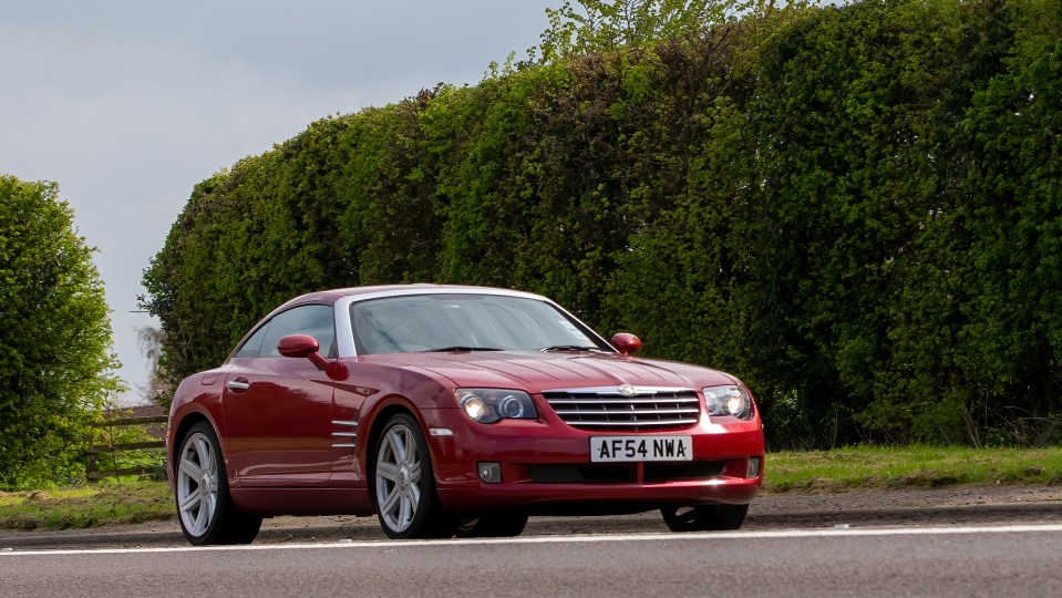 Red Chrysler Crossfire driving on a country road.