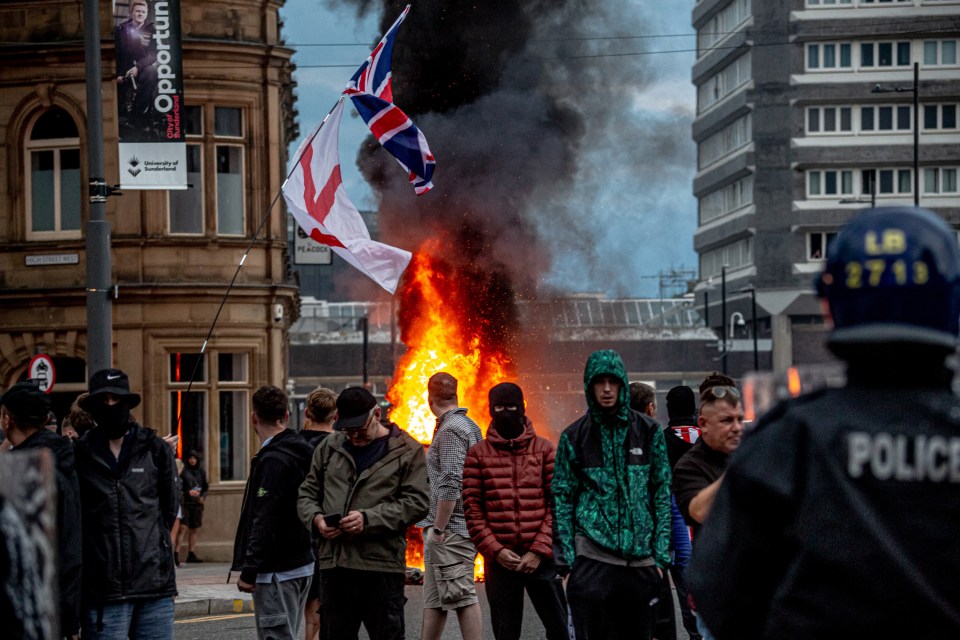Photo of a protest in Sunderland, England, with a bonfire and people holding flags.