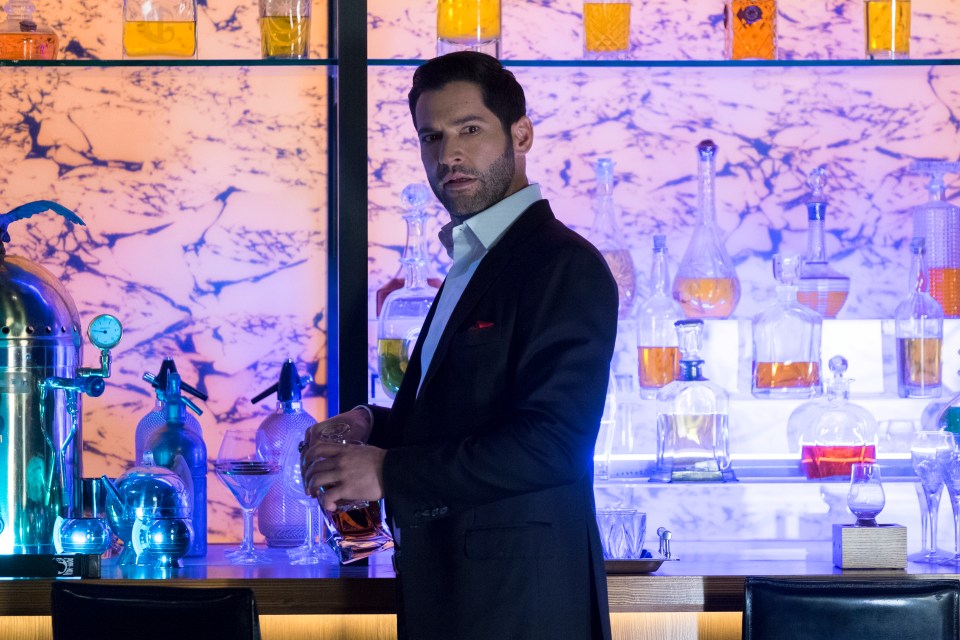 Man in suit pouring liquor behind a bar.