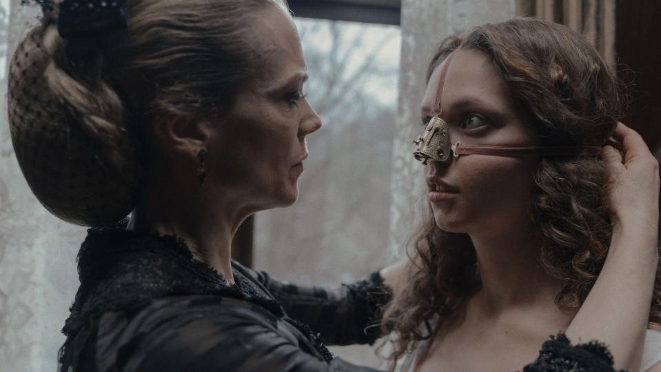 Film still of two women, one adjusting a nose device on the other.