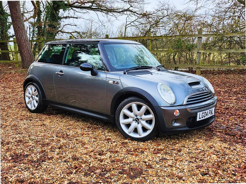 Gray Mini Cooper parked in gravel driveway.