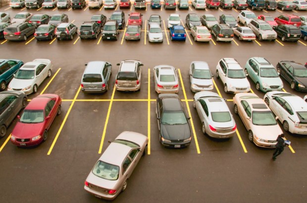 Top view looking down on parking lot, full with cars and shopper walking.