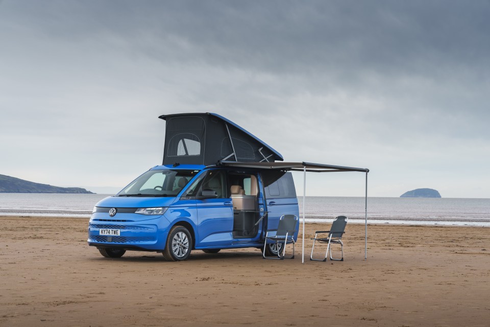 Blue plug-in hybrid campervan on a beach.