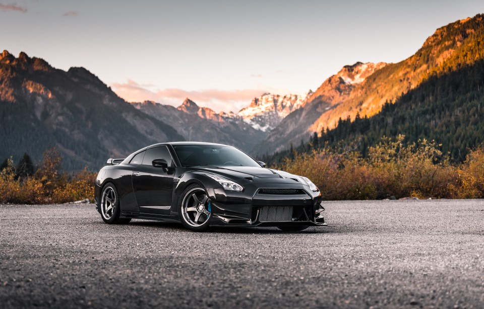 Black Nissan GT-R parked in front of mountains.