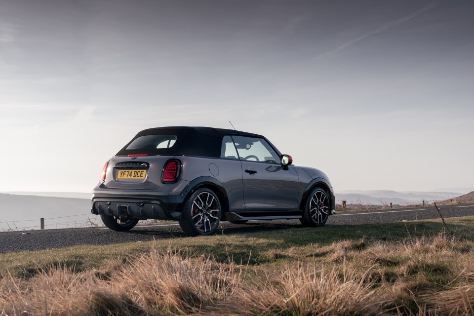 Gray Mini Cooper convertible parked on a road.
