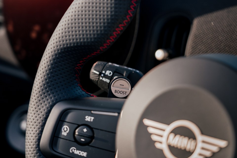 Close-up of a Mini Cooper's steering wheel controls, showing a boost button.