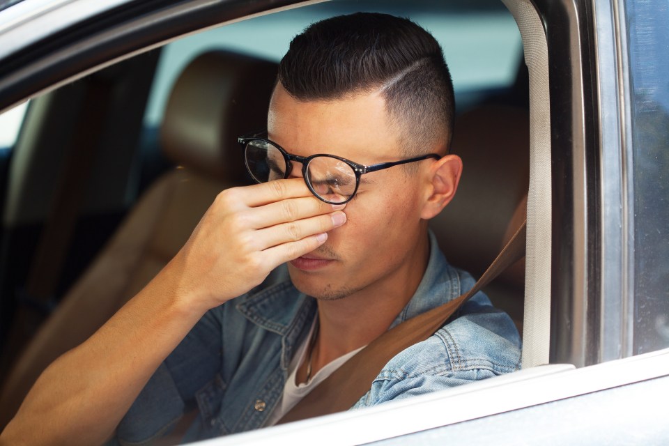 Tired driver rubbing his eyes.