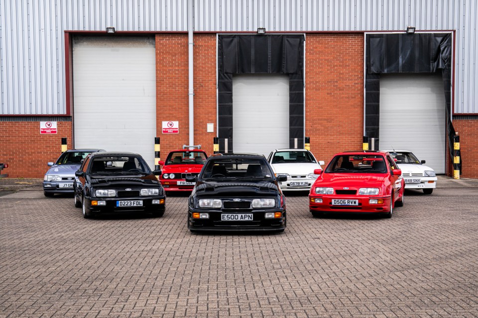 Five Ford Sierra Cosworth cars and a BMW parked in a row.