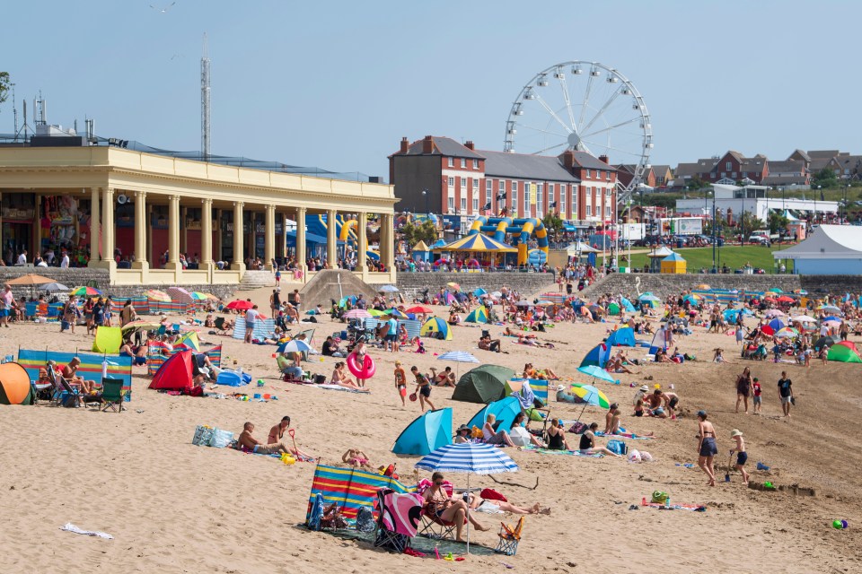 Crowded beach with people enjoying a sunny day.