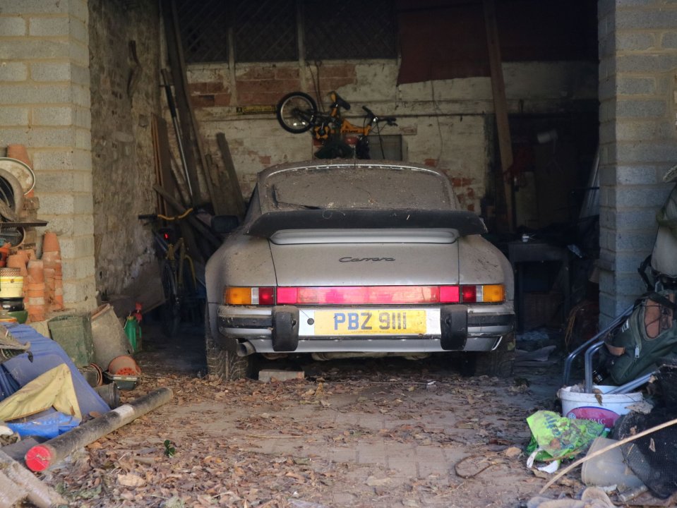 Dusty Porsche 911 Carrera in a cluttered garage.