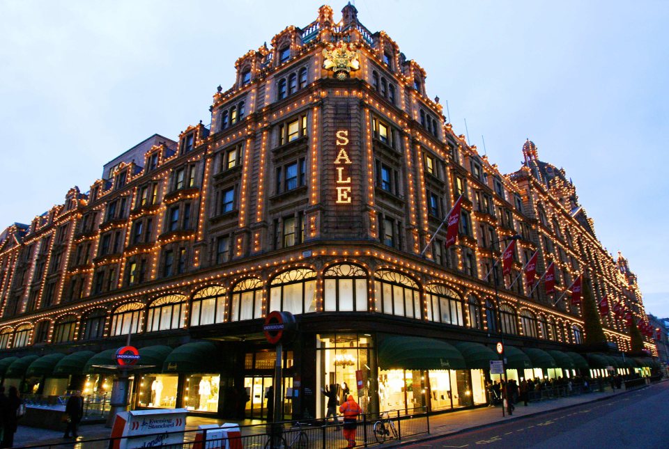 Harrods department store in London at night, illuminated with lights and displaying a "SALE" sign.