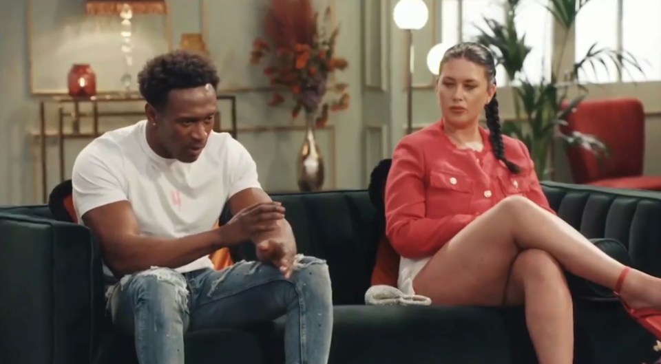 A man and woman sitting on a couch, appearing upset.