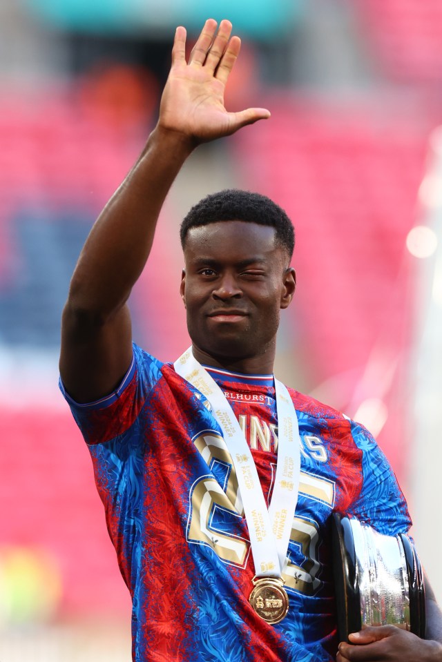 Marc Guehi of Crystal Palace celebrates, waving and holding the Emirates FA Cup.