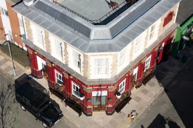 An image collage containing 1 images, Image 1 shows Aerial view of the Queen Vic pub set on the EastEnders television set in Borehamwood after an explosion, showing floral tributes outside