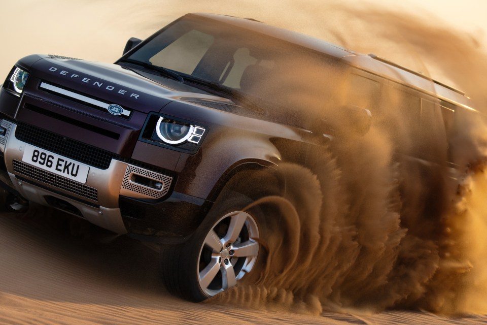 Land Rover Defender driving through sand.