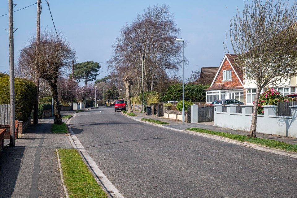 Residential street scene with houses and a red car.