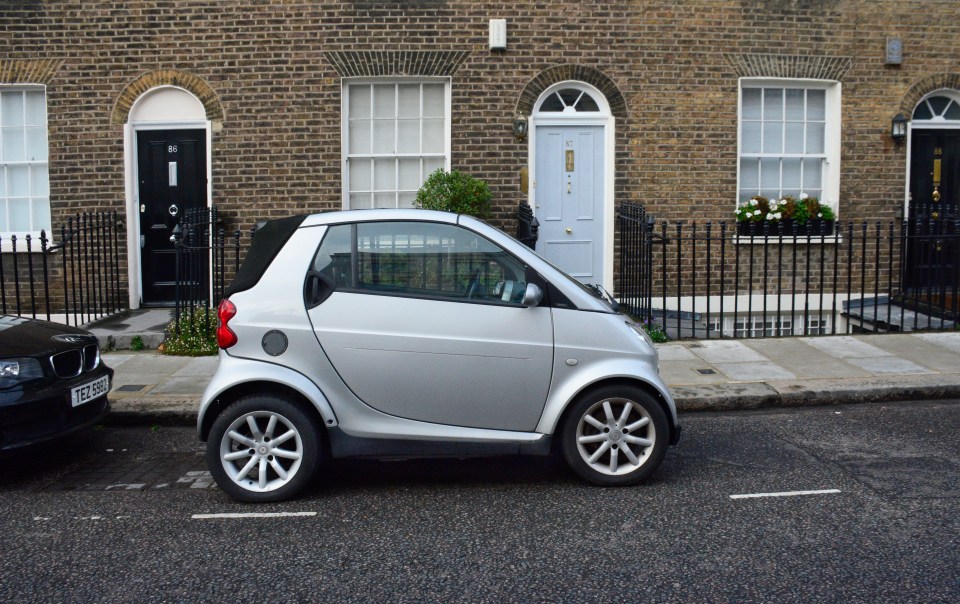 Silver Smart car parked on a London street.