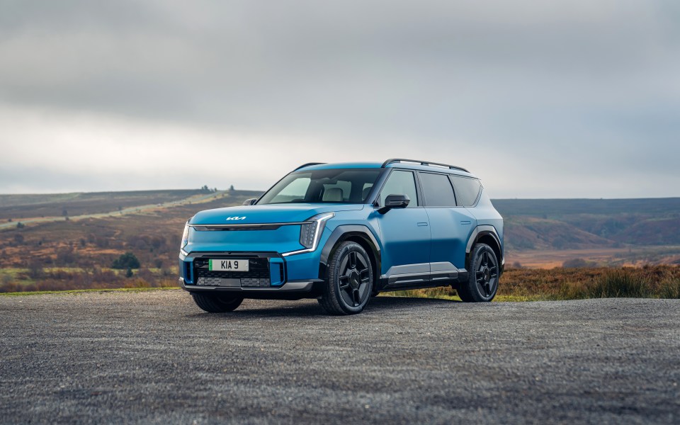 Blue Kia EV9 parked on a gravel road.