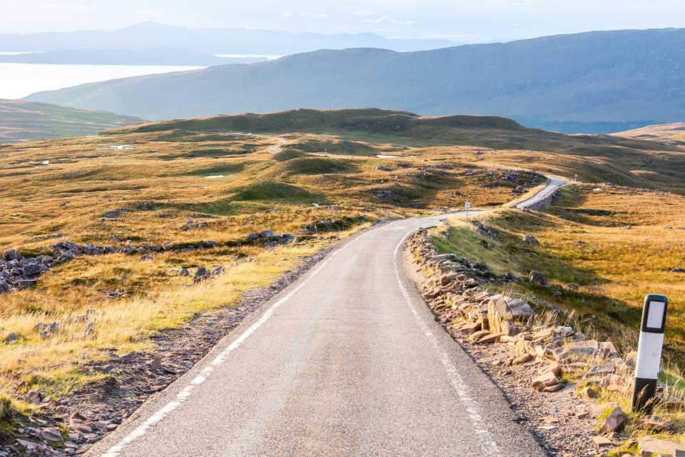 Single-track road winding through Scottish highlands with views of Raasay and Skye.