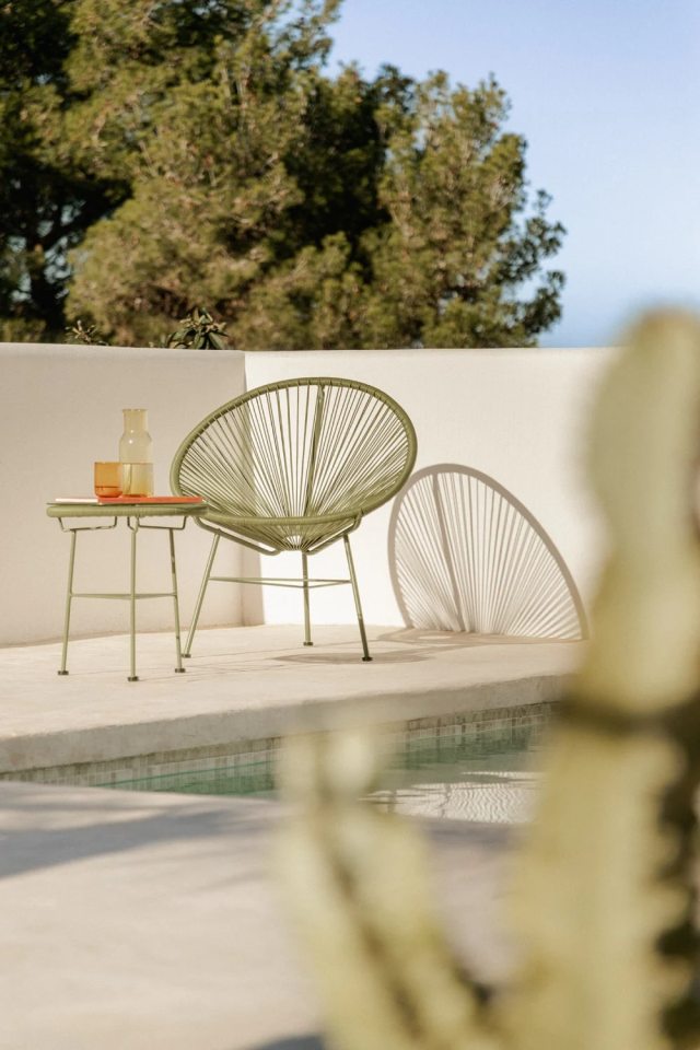 Green Acapulco chair and side table by a pool.